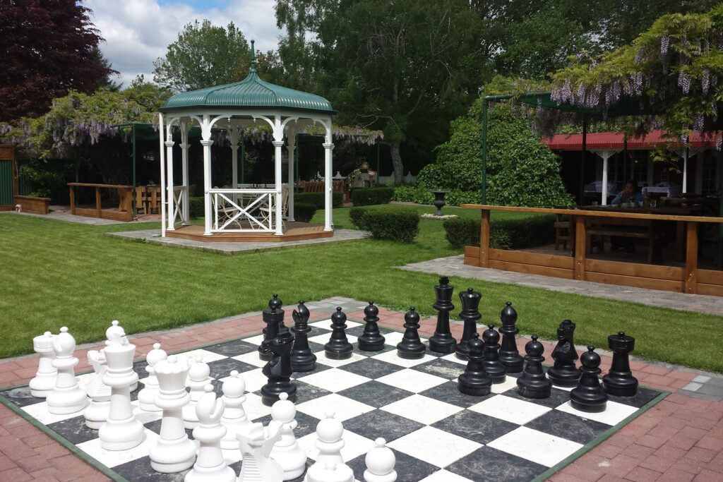Große schwarze und weiße Gartenschachfiguren auf einem Spielfeld im Park